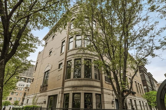 Front view of a multi-story residential building with large windows and brick exterior.