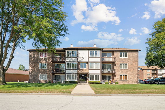 Front view of a three-story apartment building with brick exterior and balconies.