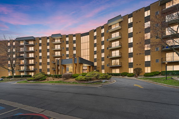 Front view of a multi-story apartment building with balconies and a central entrance.