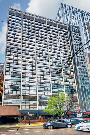 Front view of a multi-story building with glass windows and a street-level entrance.