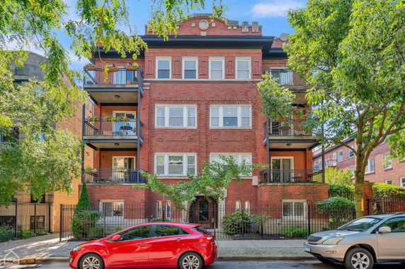 Front view of a multi-story brick apartment building with balconies.