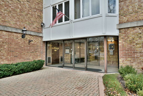 Front view of a building entrance with brick facade and glass doors.