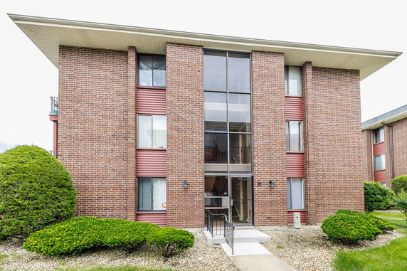 Front view of a three-story brick apartment building with multiple windows.