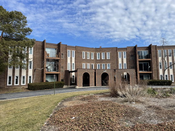 Front view of a three-story brick building with balconies and large windows.