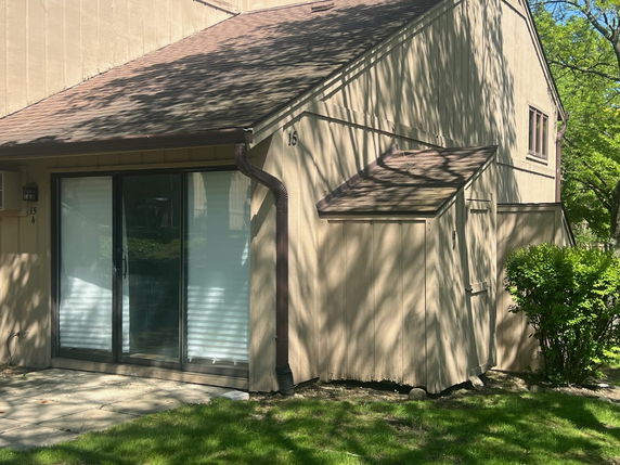 Front view of a house with a sliding glass door and pitched roof.