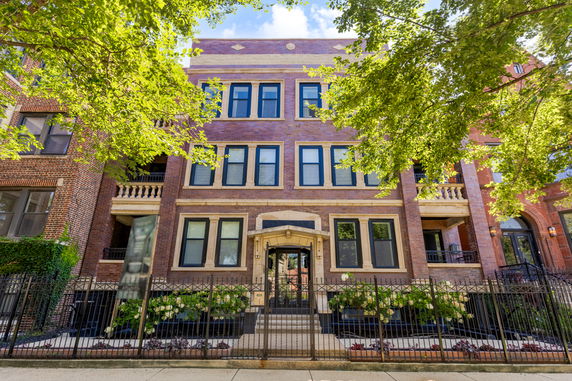 Front view of a three-story brick building with multiple windows and a gated entrance.