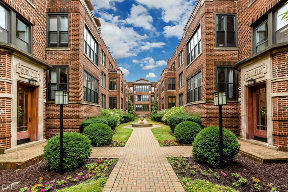 Front view of a symmetrical brick apartment building with a central courtyard and pathway.