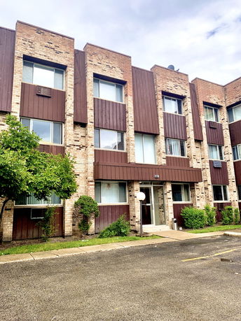 Front view of a multi-story building with brick and wood paneling.