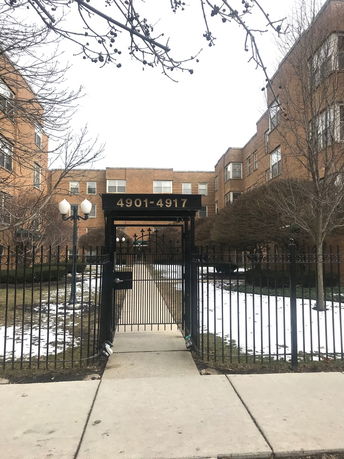 Front view of a brick apartment building with an entrance gate.