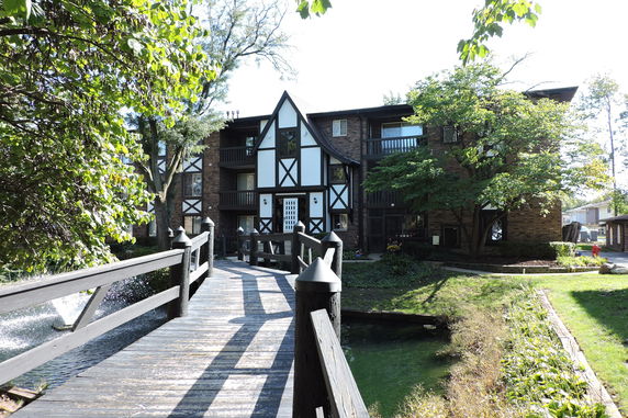 Front view of a multi-story building with a wooden walkway and Tudor-style design.