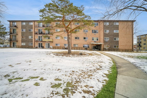 Front view of a multi-story apartment building with balconies and a main entrance.