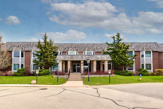 Front view of a two-story brick building with a covered entrance and shingled roof.