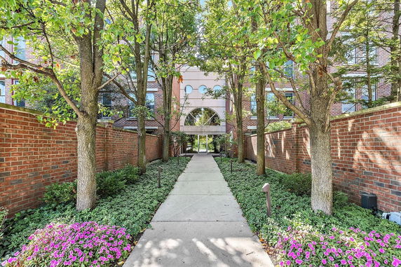 Front view of a multi-story brick building with arched entrance and surrounded by trees.