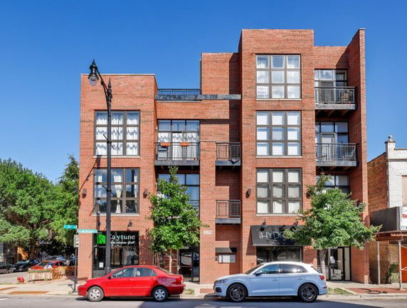 Front view of a multi-story brick building with large windows and balconies.