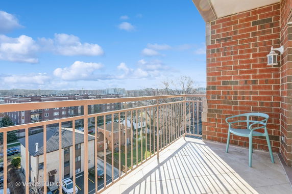 View from a balcony overlooking surrounding buildings and clear blue sky.