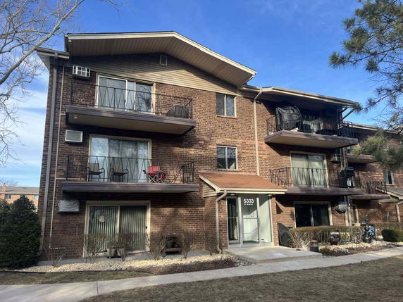 Front view of a multi-story brick building with balconies.