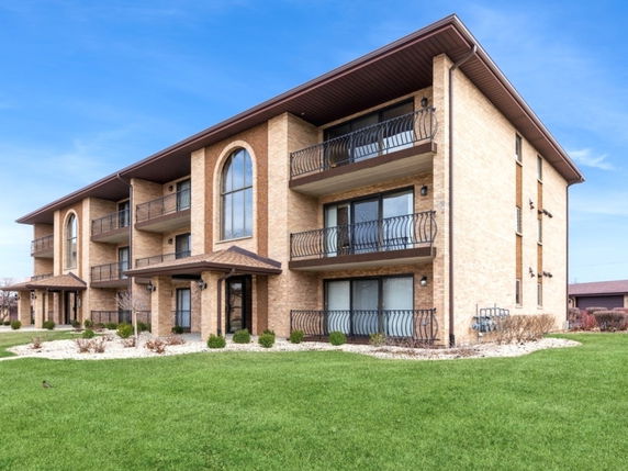 Front view of a three-story apartment building with large windows and balconies.
