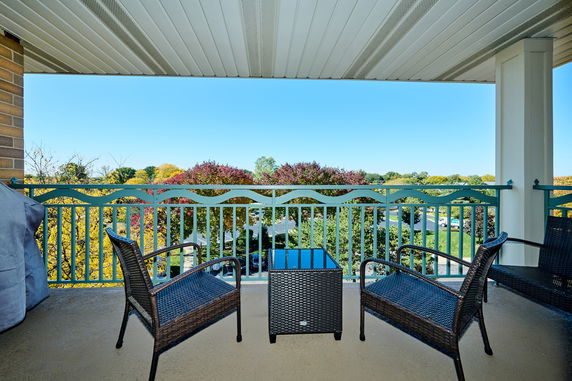View of a balcony with chairs overlooking a scenic landscape with trees.