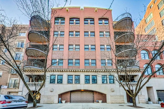Front view of a multi-story building with balconies and garage entrance.