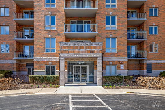 Front view of a multi-story building with brick facade and balconies.
