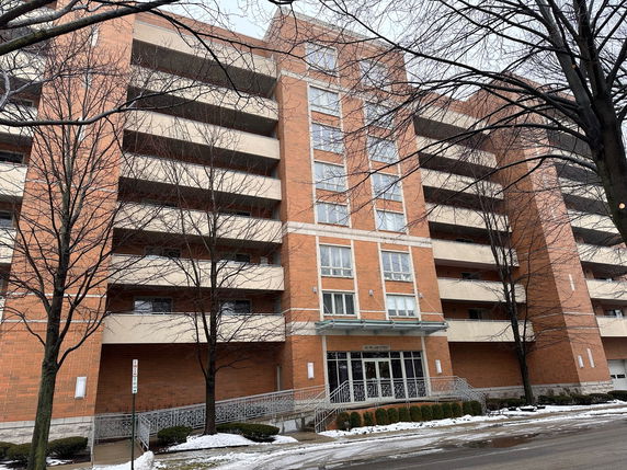 Front view of a multi-story brick apartment building with balconies.