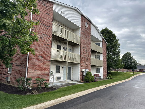 Front view of a multi-story brick apartment building with balconies.