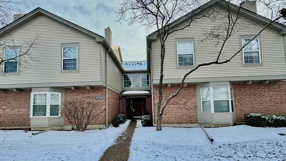 Front view of a two-story house with a central entrance and snow-covered surroundings.