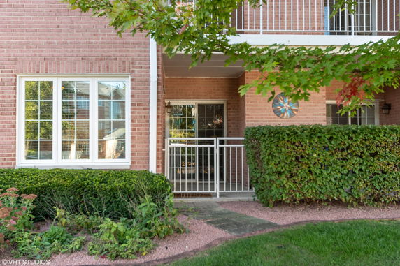 Front view of a brick building with a small porch and railing.