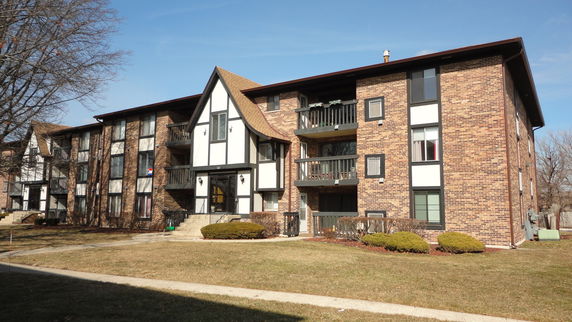 Front view of a multi-story apartment building with a brick exterior and balconies.