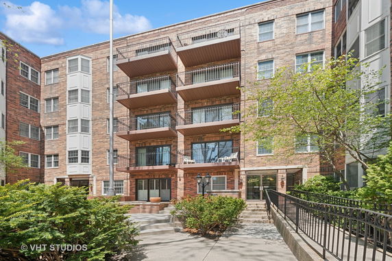 Front view of a multi-story brick apartment building with balconies.