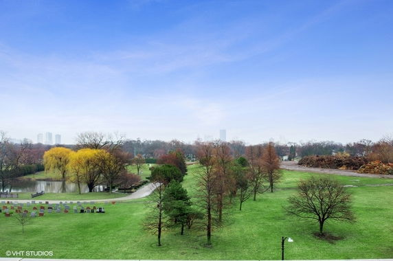 Wide view of a green park area with trees and a pathway.