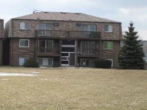Front view of a multi-story brick apartment building with balconies.