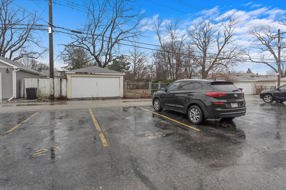 Outdoor parking space with vehicles and a small garage.