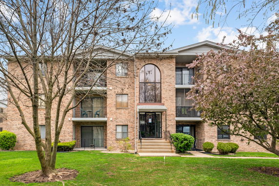 Front view of a multi-story brick apartment building with balconies.