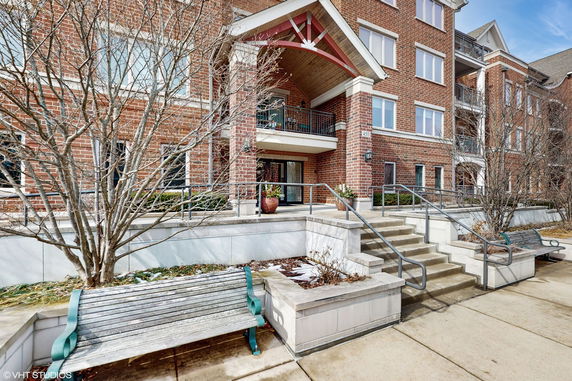 Front view of a brick multi-story building with entrance steps and a small balcony.