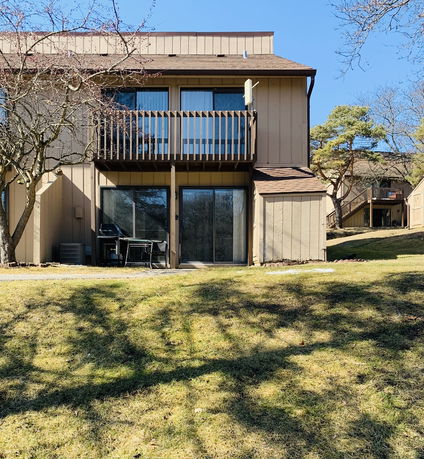 Front view of a two-story house with a wooden balcony and sliding glass doors.