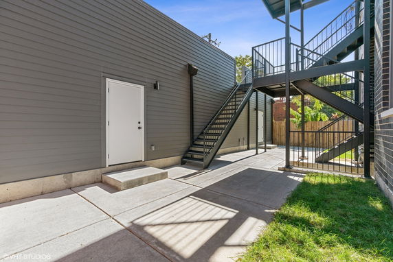 Exterior view of a building with a metal staircase and a gray siding wall.