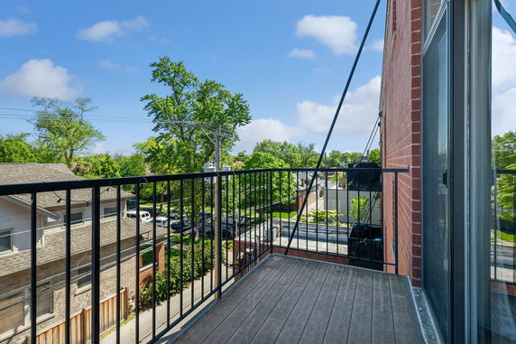 Balcony with a view of residential neighborhood and trees.