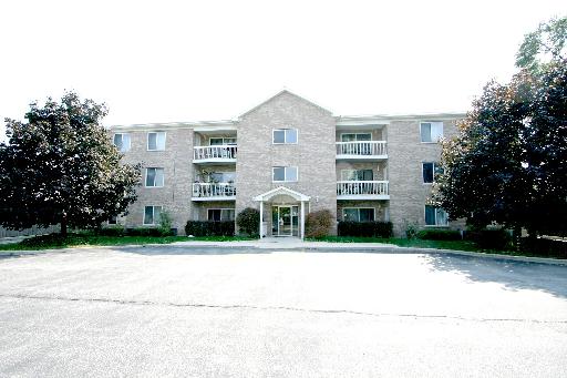 Front view of a three-story brick apartment building with balconies.