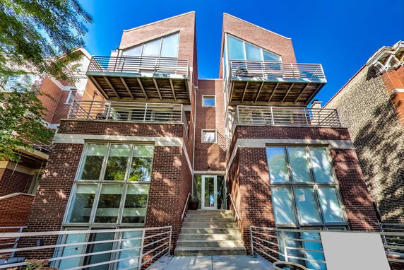 Front view of a modern multi-story brick building with large windows and balconies.