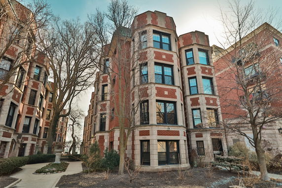 Front view of a multi-story brick apartment building with large windows.