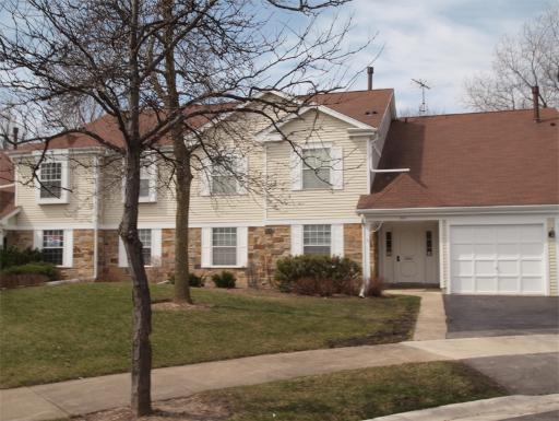 Front view of a two-story house with a garage and brown roof.