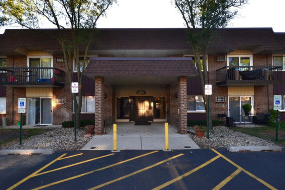 Front view of a two-story brick building with a central entrance and balconies.