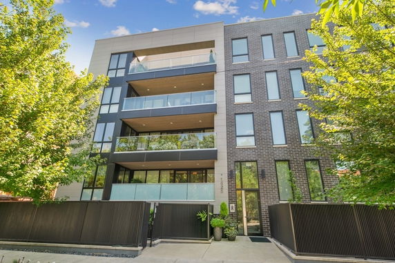 Front view of a modern multi-story building with balconies and large windows.