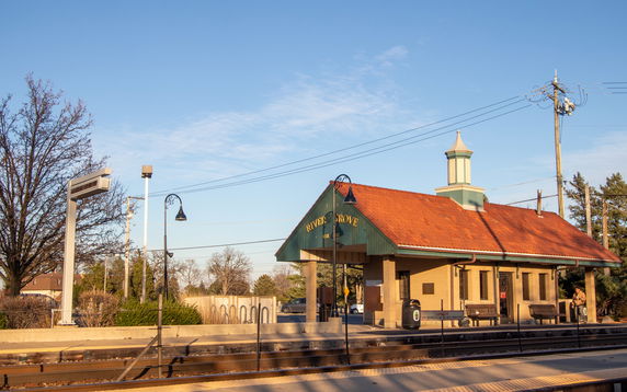 Front view of a small train station building with a red roof and a cupola.