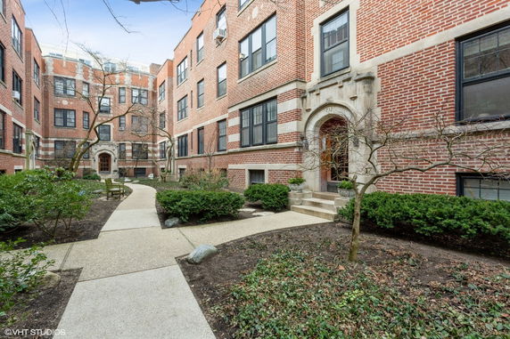 Front view of a brick apartment building with an arched entrance.