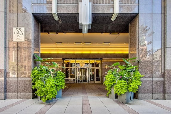 Front entrance of a building with large glass doors and potted plants.