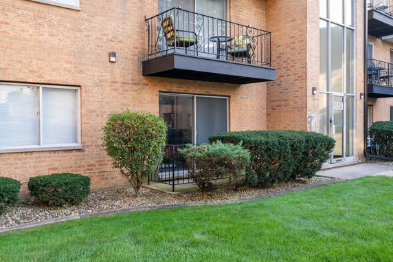 Front view of a multi-story building with balconies and glass doors.
