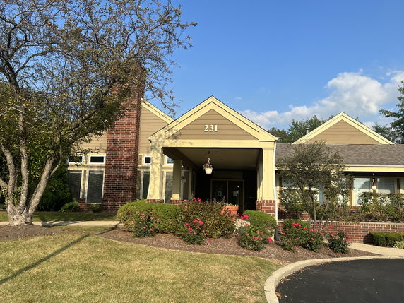 Front view of a single-story building with a brick chimney and entryway.