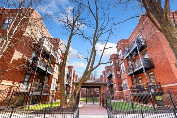 Front view of a multi-story brick apartment building with balconies.